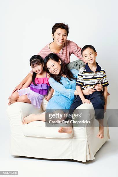 portrait of a mid adult man and a young woman sitting in an armchair with their son and daughter - front view portrait of four children sitting on rock stock-fotos und bilder