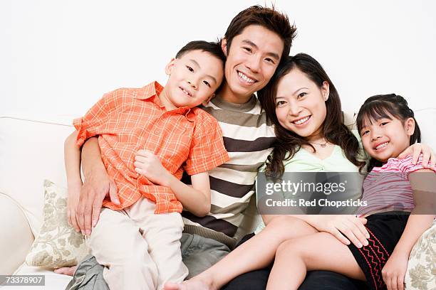 portrait of a mid adult man and a young woman sitting on a couch with their son and daughter - front view portrait of four children sitting on rock stock-fotos und bilder