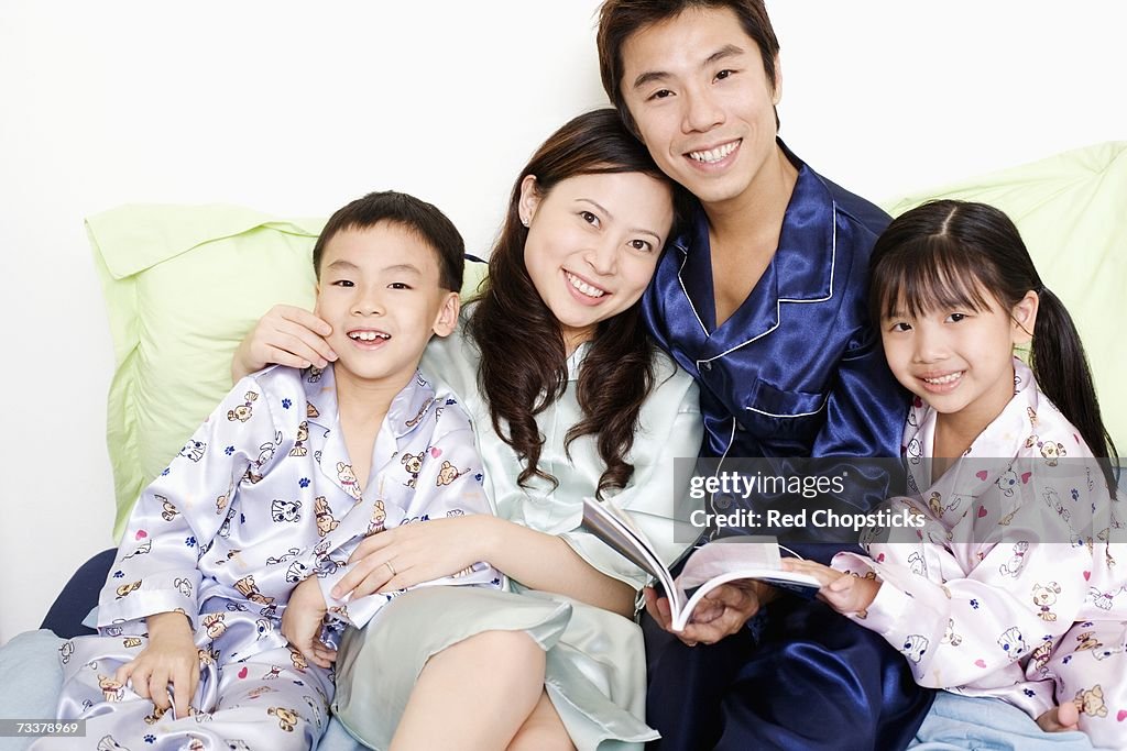 Portrait of a boy and a girl smiling with their parents on the bed