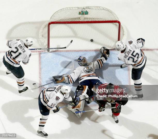 Jussi Markkanen of the Edmonton Oilers lies spread eagle on the ice with the puck in the net behind him as teammates Jason Smith;Jan Hejda and Shawn...