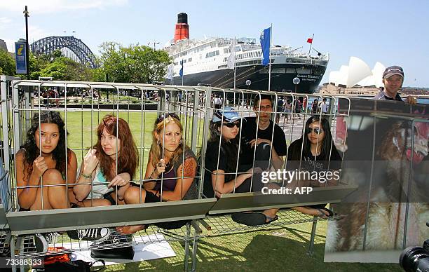 Animal rights activists sit in cages during a protest at Sydney Harbour, with the luxury Queen Elizabeth ocean liner in the backgroud, to mark the...