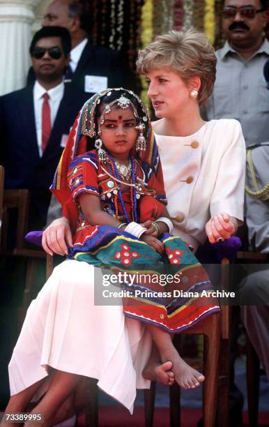 Local girl wearing traditional costume sits on the Princess of Wales' lap during her visit to Lallapet High School in Hyderabad, India, February...