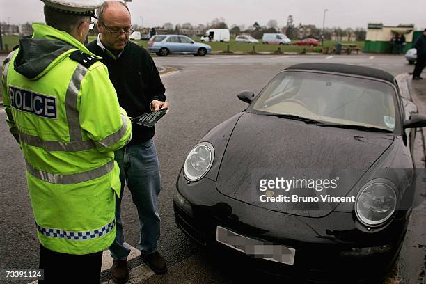 Police officer hands a leaflet to a driver caught using his telephone whilst driving, as part of a drive to inform motorist of the risk on February...