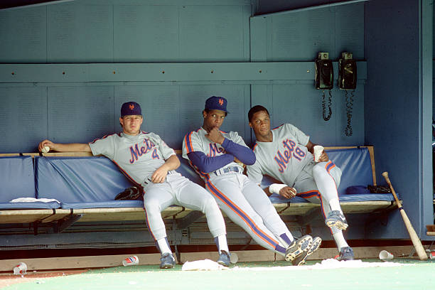 Outfielders Lenny Dykstra and Darryl Strawberry of the New York Mets sit in the dugout with pitcher Dwight Gooden during a game against the...