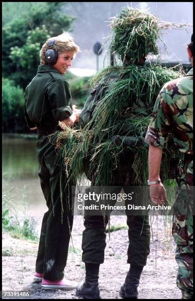 The Princess of Wales talking to a camouflaged soldier during a visit to the Royal Hampshire regiment at Tidworth, June 1988. The Princess wore a...