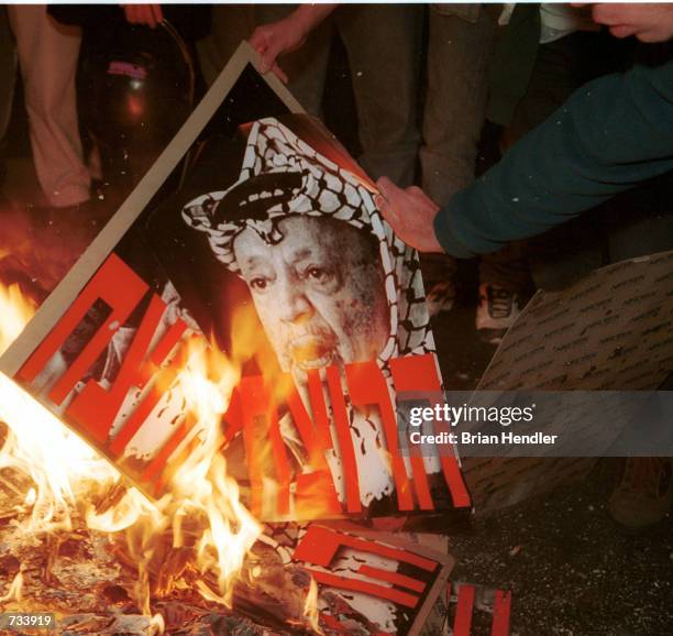 Right-wing Israeli demonstrators burn posters of Palestinian leader Yasser Arafat with the Hebrew word "Murderer" in red letters, on a street in...