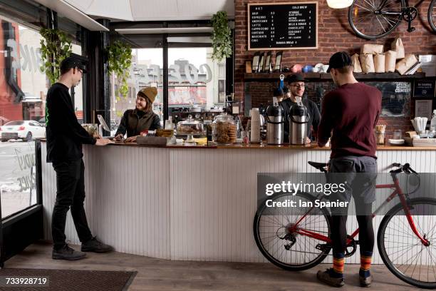 employees serving customers in cafe, nike and coffee shop, new york, usa - partnership men bikes stockfoto's en -beelden