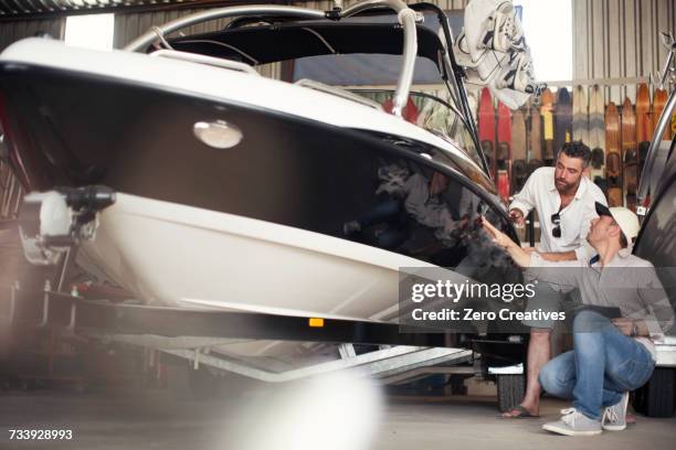 two men checking motor boat bodywork in repair workshop - repairing boat stock pictures, royalty-free photos & images