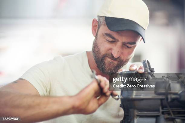 man repairing outboard motor in boat repair workshop - repairing boat stock pictures, royalty-free photos & images