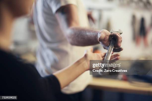 over shoulder view of man handing wrench in boat repair workshop - outil de bricolage photos et images de collection