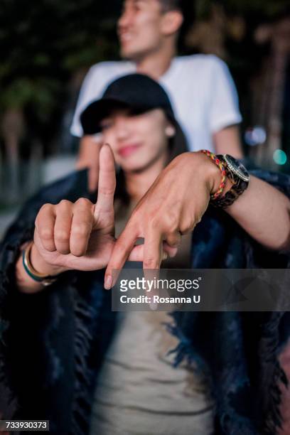 portrait of young woman making la hand gesture outside los angeles county museum of art at night - hollywood california stock-fotos und bilder