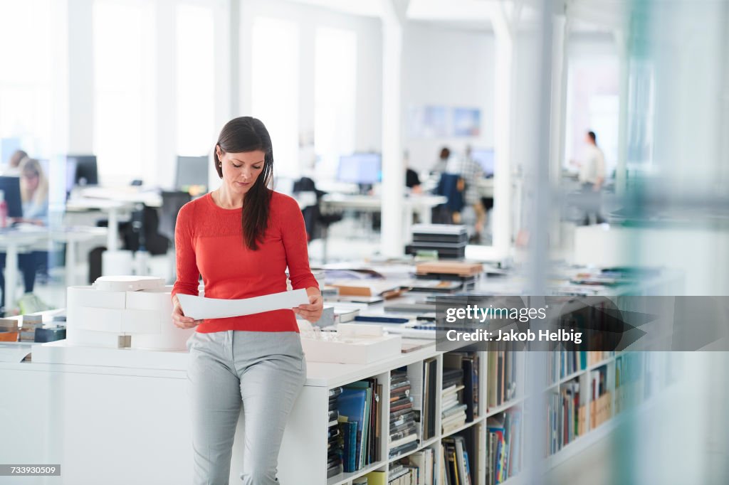 Businesswoman in office looking at blueprints