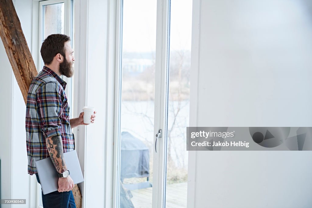 Young male designer looking through window in design studio