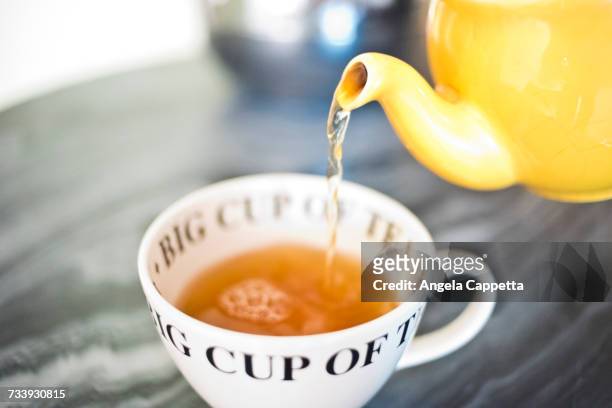 tea pouring into teacup from teapot - ティーポット ストックフォトと画像