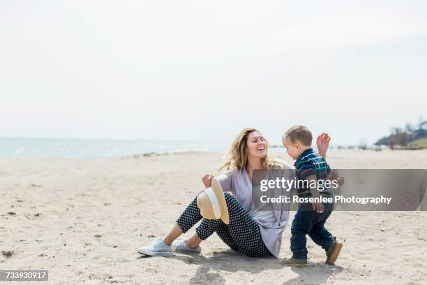 young woman sitting on beach playing with toddler son - oshawa 個照片及圖片檔