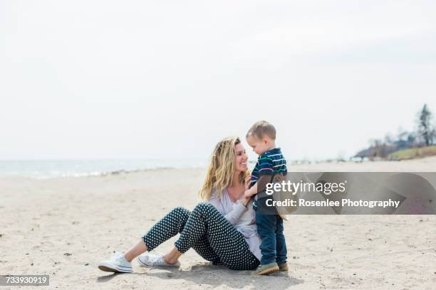 young woman sitting on beach playing with toddler son - oshawa 個照片及圖片檔