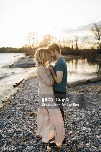 couple beside lake, face to face, holding hands - whitby ontario canada stock pictures, royalty-free photos & images