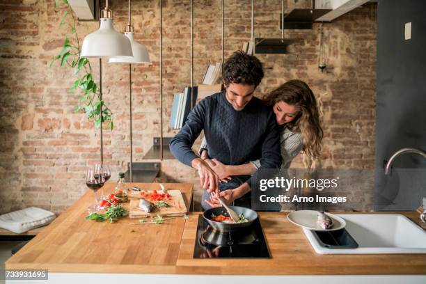 young couple cooking fish cuisine at kitchen counter hob - kitchen bench top stock pictures, royalty-free photos & images