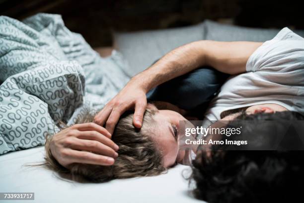 young couple lying in bed embracing face to face - man and woman cuddling in bed stockfoto's en -beelden