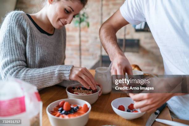 young couple preparing breakfast together at kitchen counter - yoghurt stock pictures, royalty-free photos & images