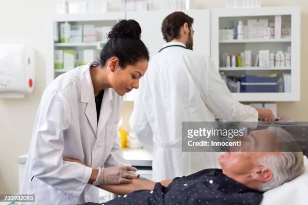 doctor extracting patients blood with syringe - entfernen stock-fotos und bilder