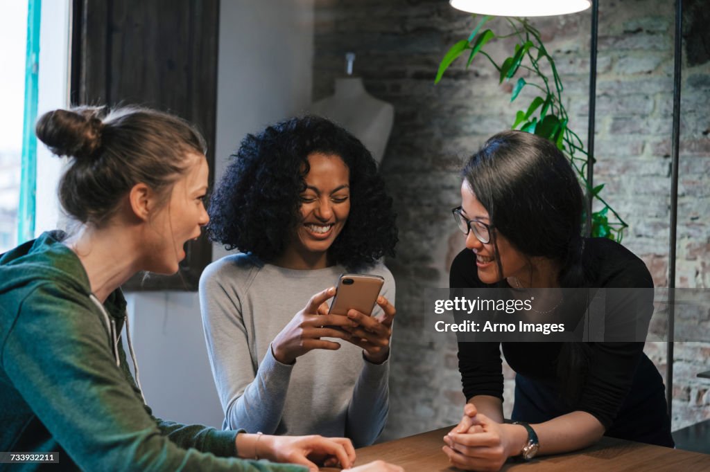 Friends looking at mobile phone smiling