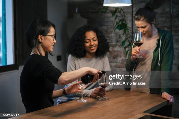 friends sharing a bottle of red wine - girls night in stock pictures, royalty-free photos & images