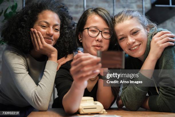 friends looking at instant film photograph smiling - girls night in stock pictures, royalty-free photos & images