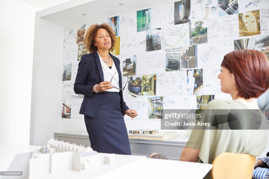 Female architect explaining to colleague in office meeting