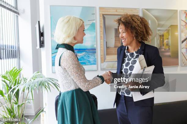 female designer greeting female client in office lobby - hospitality lounge at the longines global champions tour of london stockfoto's en -beelden