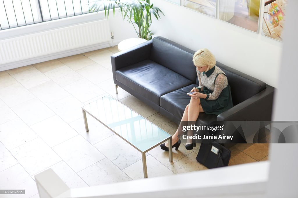 High angle view of woman sitting on sofa in design office lobby