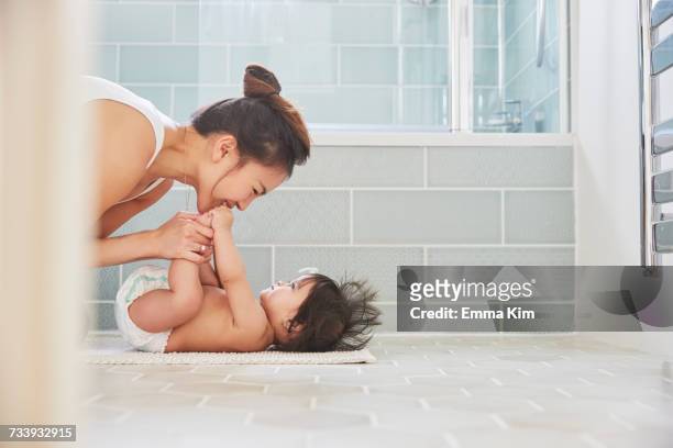 woman playing with baby daughters feet on bathroom floor - chinese family with one child stock pictures, royalty-free photos & images