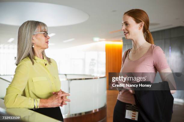 businesswomen talking in reception area of office - black blouse stock pictures, royalty-free photos & images