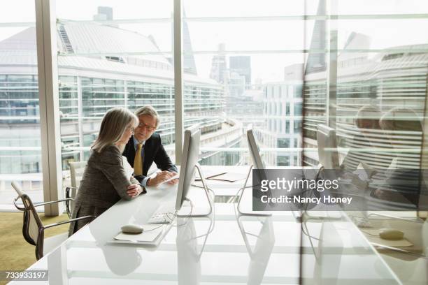 businessman and businesswoman reading and analysing report, london, uk - business people and paper imagens e fotografias de stock