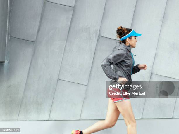 mature female ultra runner running in city - ultra motivated fotografías e imágenes de stock