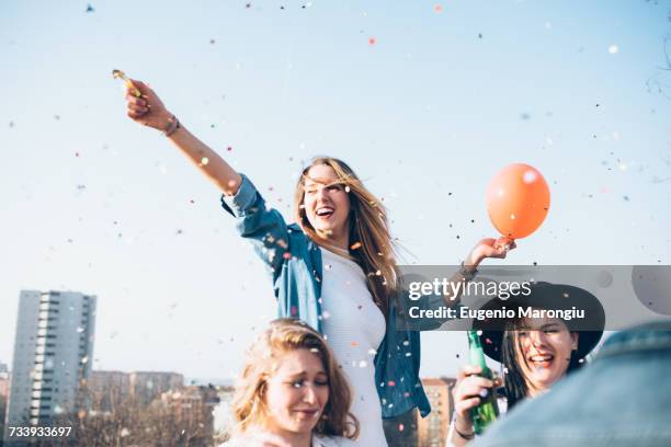 group of friends enjoying roof party, confetti in air - candid city stock-fotos und bilder