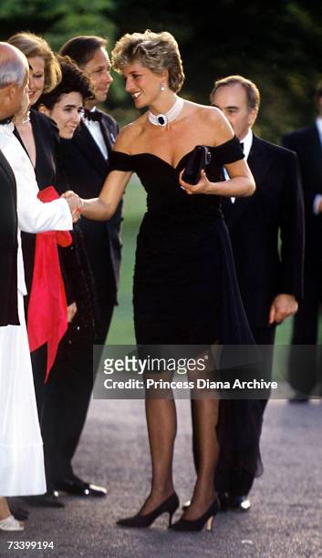 Princess Diana arriving at the Serpentine Gallery, London in a gown by Christina Stambolian, June 1994. Standing behind her is property developer and...