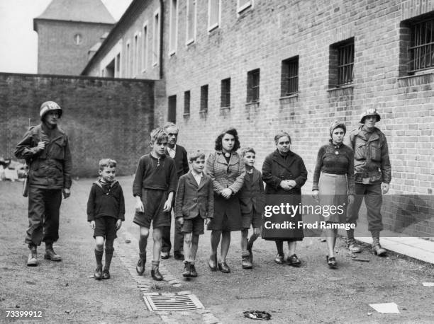 American military police officers with 14 year-old Willy Etschenberg and members of his family in a prison courtyard in Aachen, October 1944....