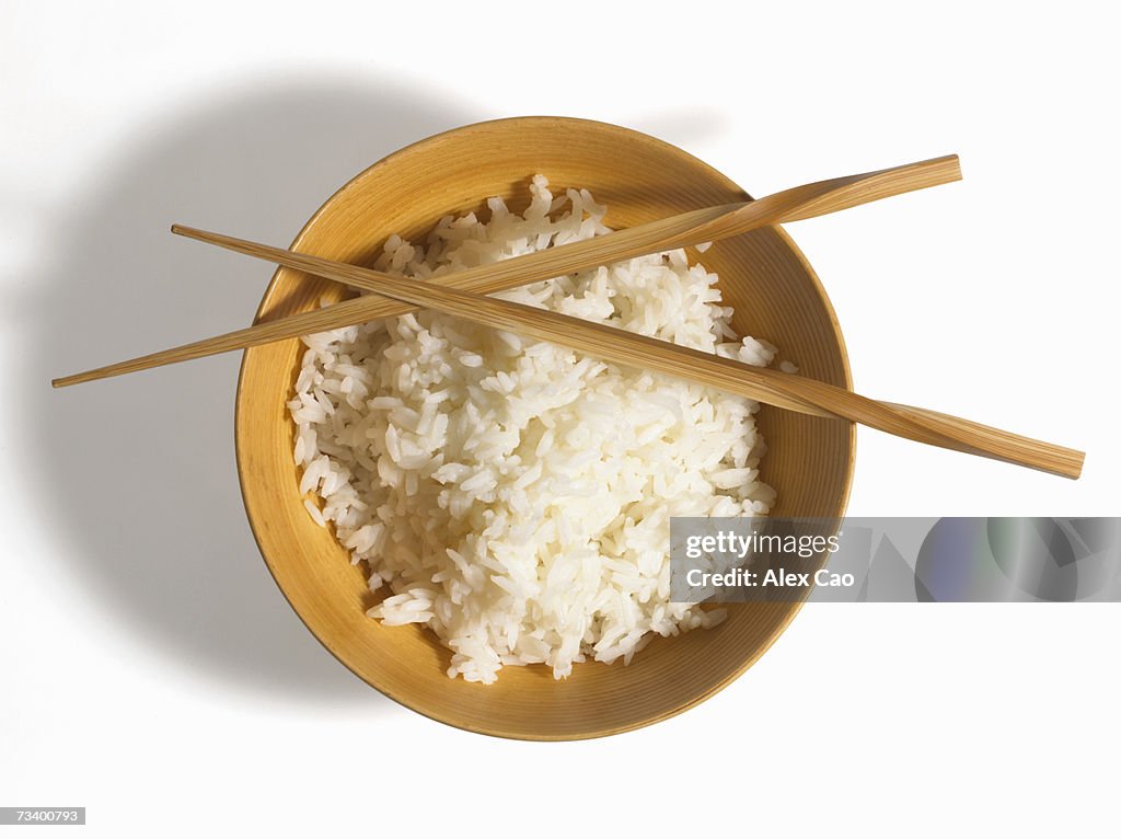 Boiled rice in bowl with chopsticks