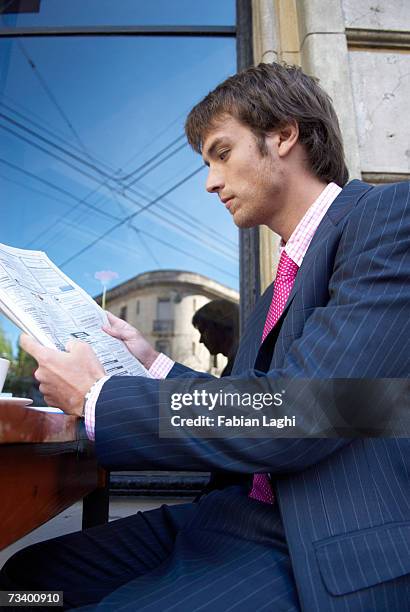 young businessman reading newspaper in caft - caft stock pictures, royalty-free photos & images