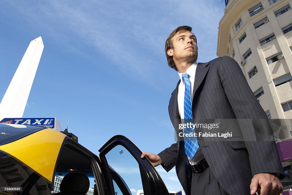 Young businessman getting into taxi