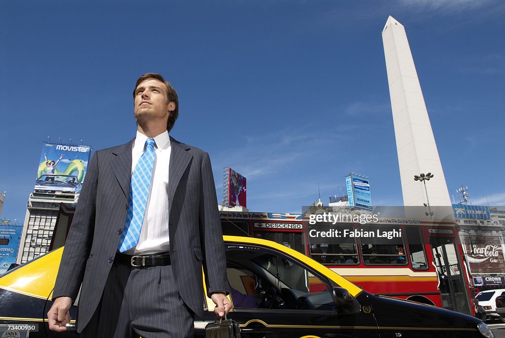 Young businessman standing by taxi, low angle view
