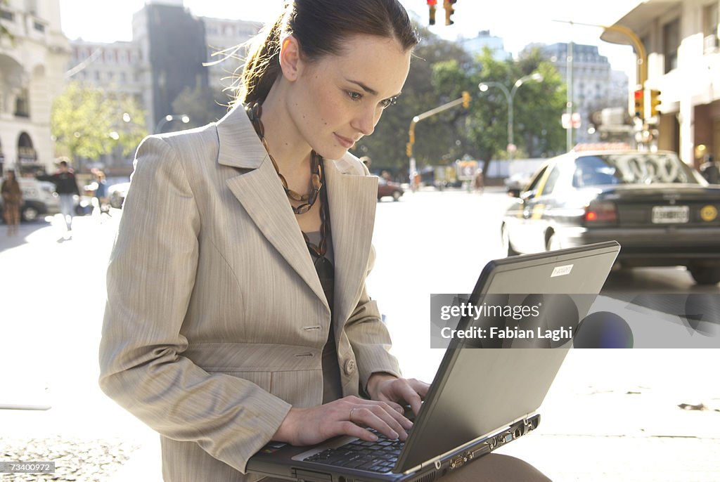 Young businesswoman using laptop outdoors