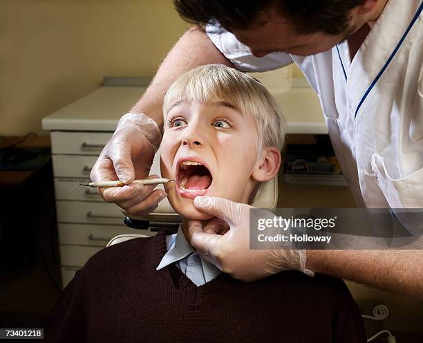 dentist examining boy's (12-14) teeth, patient looking worried - dentista bambini foto e immagini stock