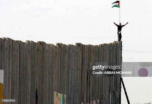 Palestinian man exults while standing on top of a section of Israel's controversial separation barrier during clashes erupted after the Friday...