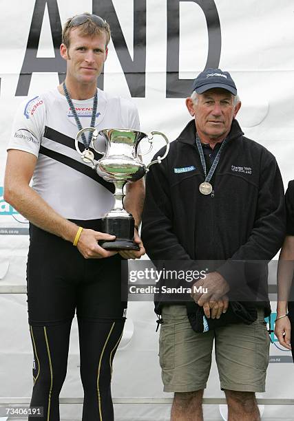 Mahe Drysdale of Auckland holds the cup with Coach John White on the podium after winning the Mens Premier Single Sculls Final during the New Zealand...