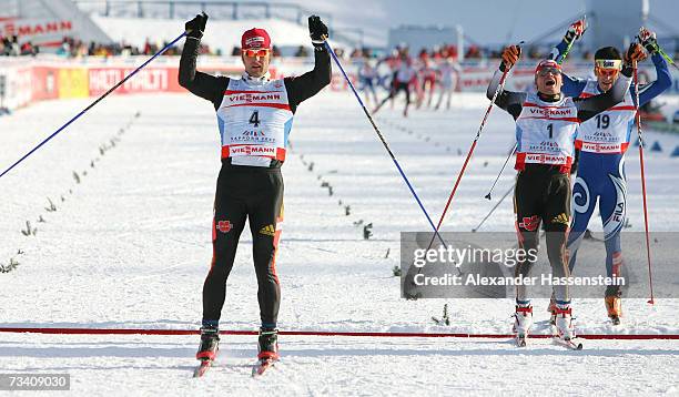 Axel Teichmann of Germany celebrates winning the first place whilst Tobias Angerer of Germany celebrates his 2nd place and Pietro Piller Cottrer of...