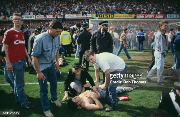 St John Ambulance volunteer attends to a casualty on the pitch at Hillsborough football stadium in Sheffield, after a human crush at an FA Cup...