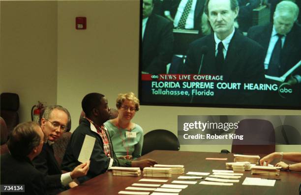 County workers continue the manual recount of presidential ballots while watching the Florida Supreme Court ballot issue hearing on television...