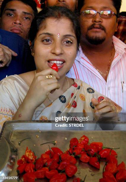 Indian woman Annandita Dutta Tamuly is watched by a crowd as she consumes Bhut Jolokia Chili Peppers for a television programme in Guwahati, 25...